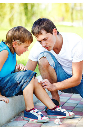 Father cleaning son's wounded knee