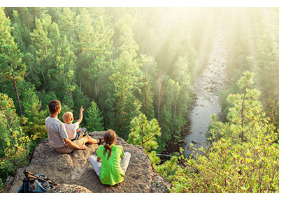 Family resting on a rock looking at the river view below